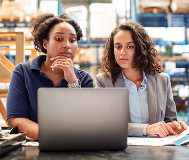 Female worker with supervisor working on laptop